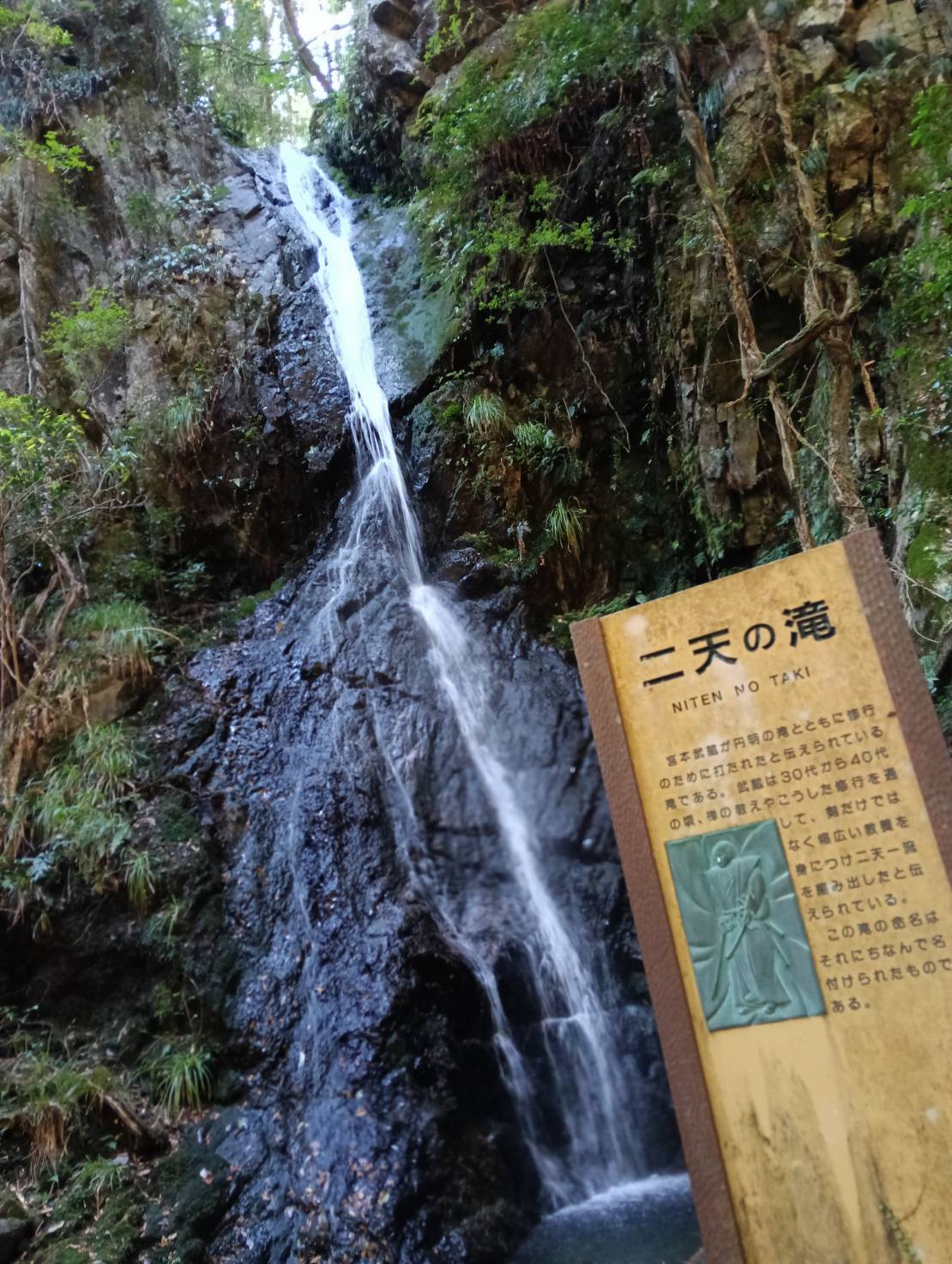 二天の滝の流れと、宮本武蔵の伝説を記した看板
